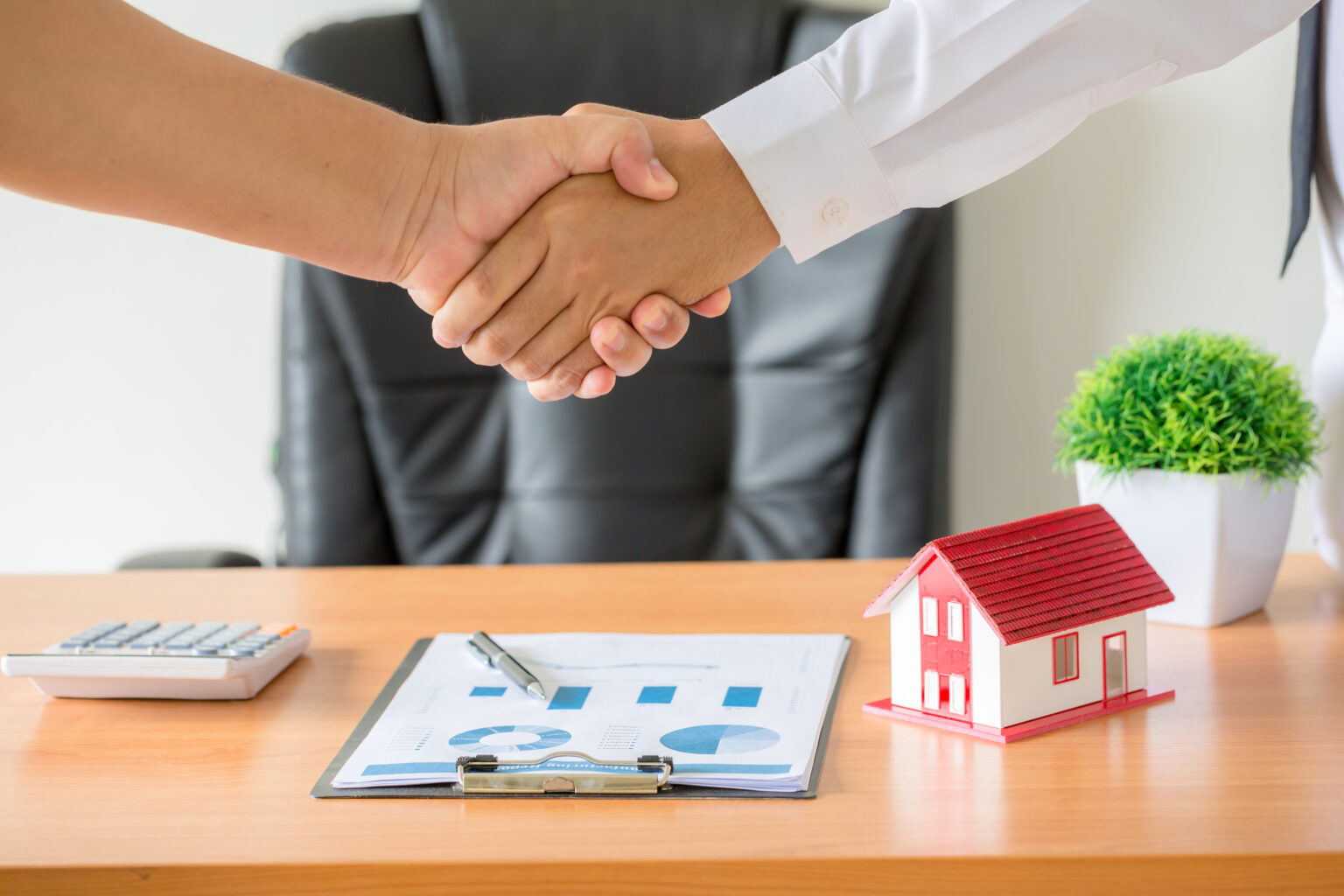 Hands of agent and client shaking hands after signed contract bu
